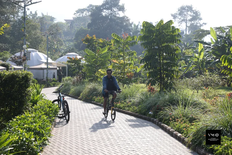 Participants cycling along a garden path lined with planting — CAMP 2023, PT. Agrinesia Raya