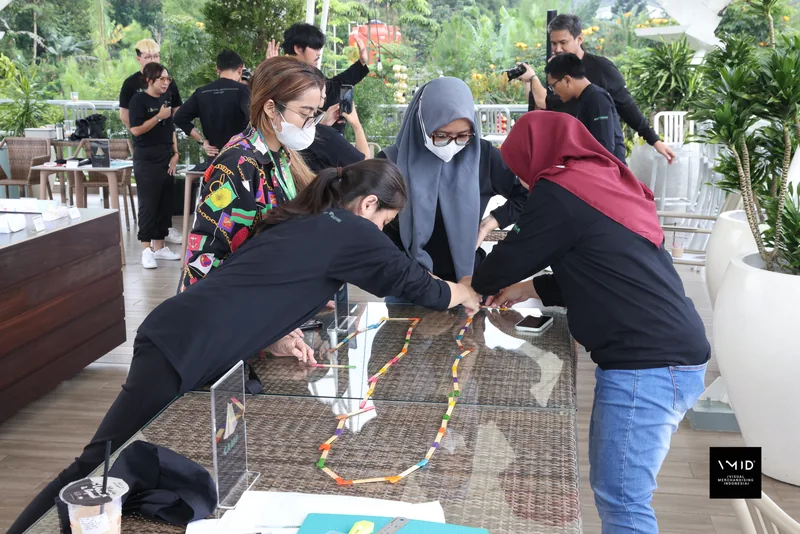 Four participants laying a chain of coloured pieces across a table during a group exercise — CAMP 2023