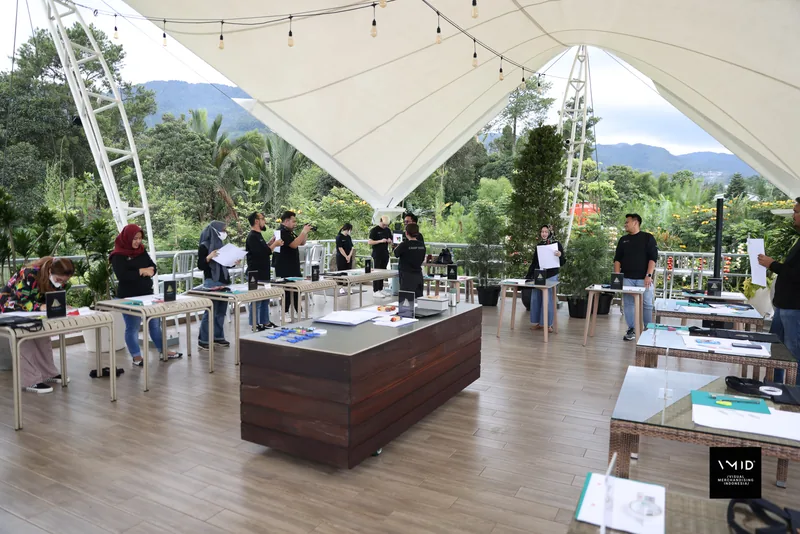 Participants at worktables under the white canopy of an open-air pavilion, hills behind — CAMP 2023, PT. Agrinesia Raya