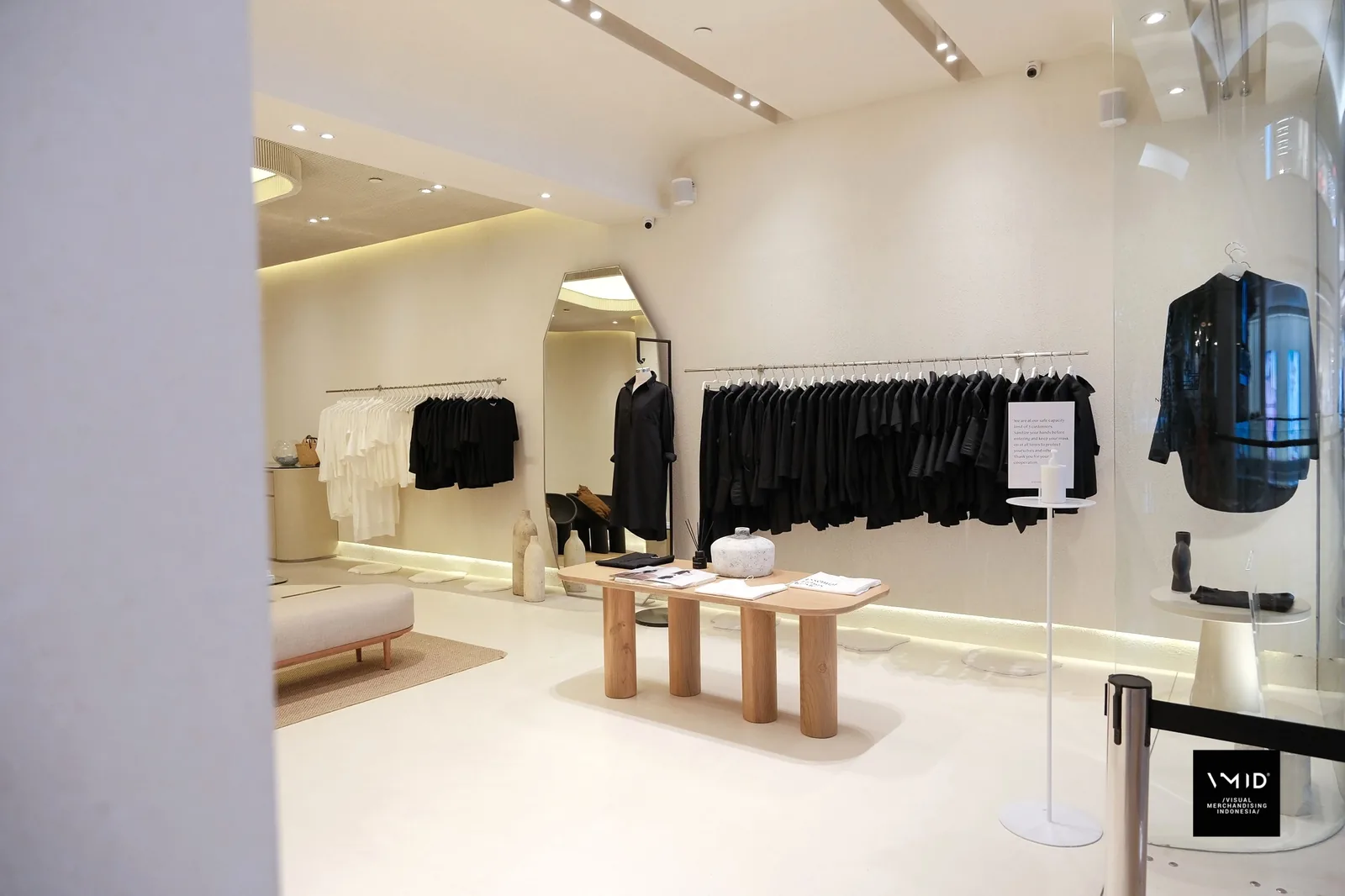 Inside Masshiro&Co.: black and white shirts on wall rails, a timber table of folded pieces, a mannequin in black and a jacket hung in the window — 2022